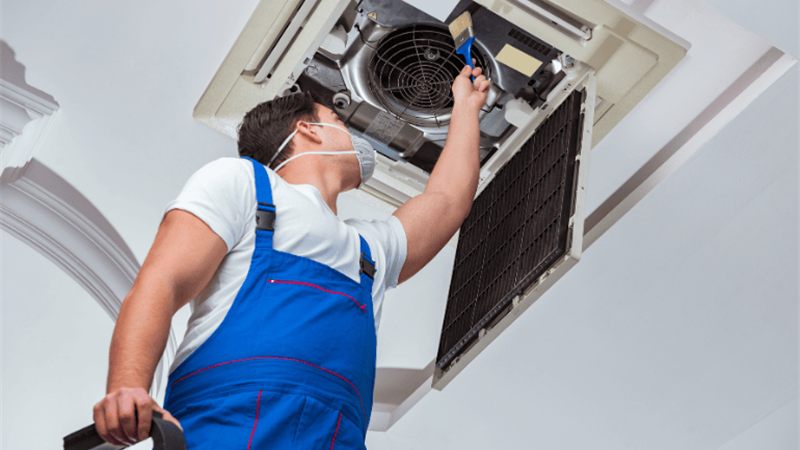 Técnico da SonoAr fazendo manutenção de ar-condicionado cassete no teto